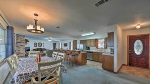 A spacious living area with a dining table, kitchen, and a large wooden door. - Lakefront Livingston Home w/ Dock, 1 Mi to Launch! (Livingston)