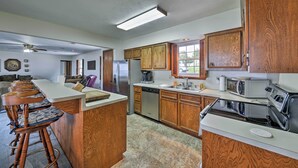 A kitchen with wooden cabinets, a central island with stools, a refrigerator, microwave, stove, and dishwasher. - Lakefront Livingston Home w/ Dock, 1 Mi to Launch! (Livingston)
