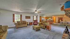 A spacious living room with a high ceiling, a ceiling fan, and a view of the kitchen in the background. - Lakefront Livingston Home w/ Dock, 1 Mi to Launch! (Livingston)