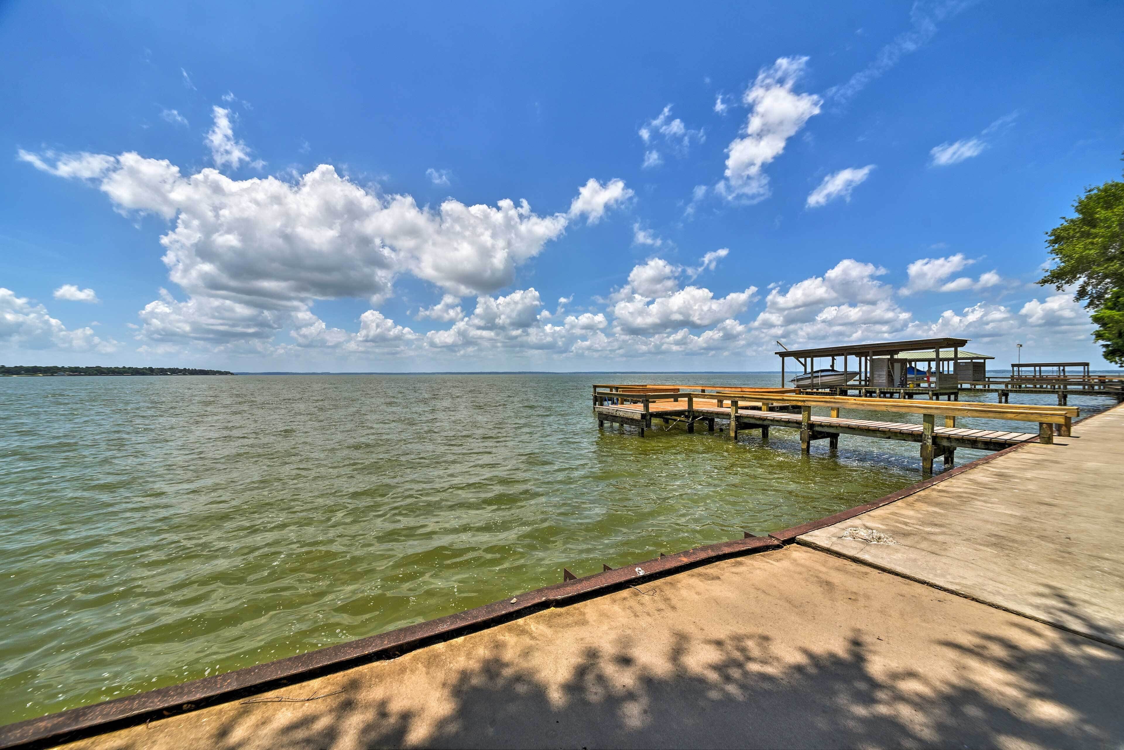 A wooden pier extending into a calm lake with a clear sky.