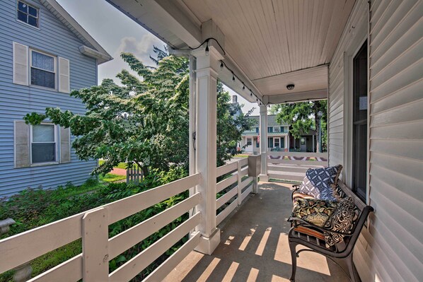 A porch with a bench, white railings, and a view of neighboring houses.