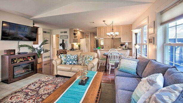 A spacious living room with a fireplace, a sofa, a coffee table, and a television. There is a dining area with a table and chairs. The kitchen is visible in the background. - 9 Mi to Midtown Harrisburg: Cottage w/ Deck (Harrisburg)