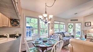 A dining area with a table set for four, surrounded by white chairs with green cushions. A chandelier hangs above the table, and a wreath is displayed on the wall. - 9 Mi to Midtown Harrisburg: Cottage w/ Deck (Harrisburg)