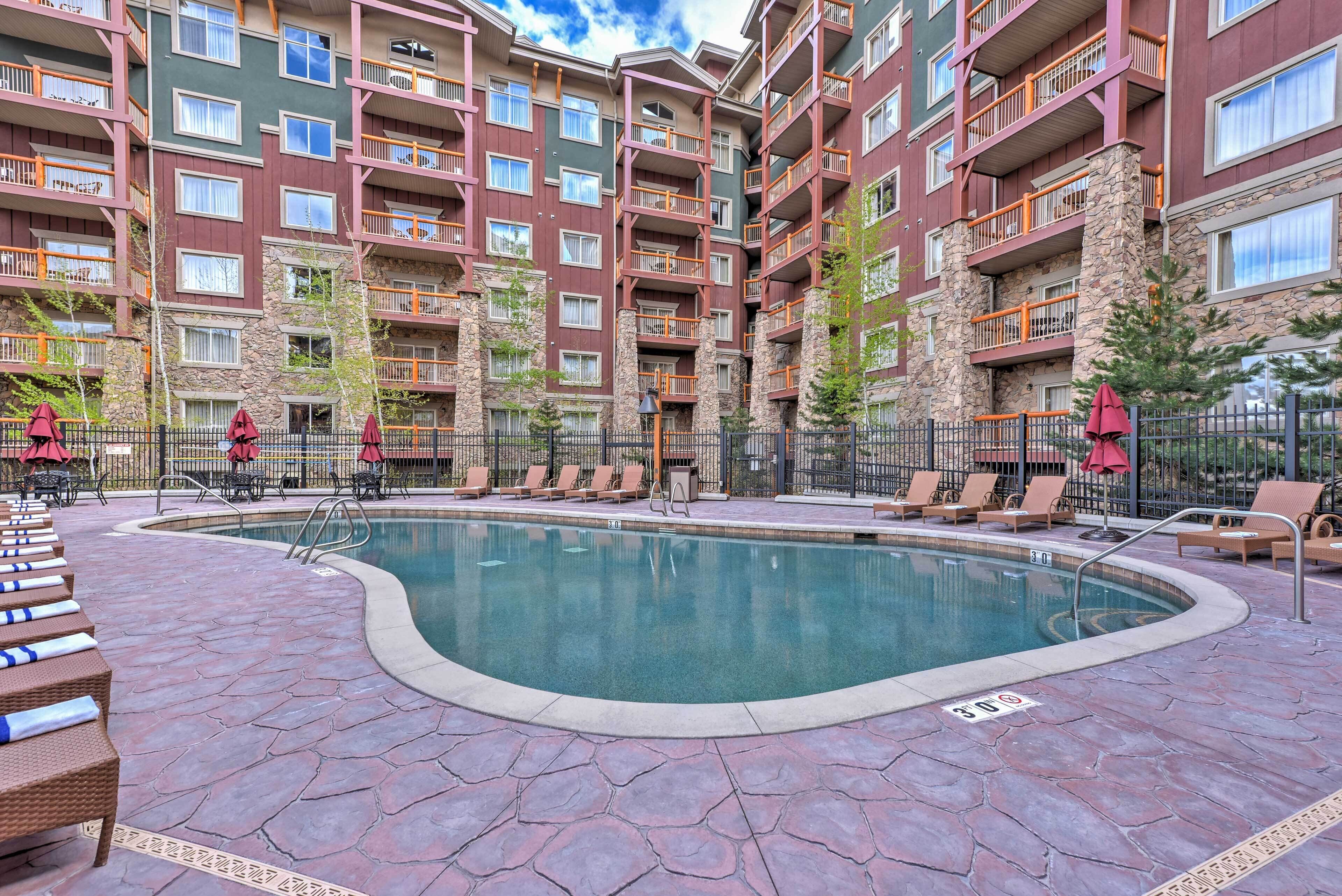 Un hotel de varios pisos con piscina, mobiliario exterior y fachada de piedra.