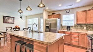 A spacious kitchen with a large island, wooden cabinets, stainless steel appliances, and pendant lighting.