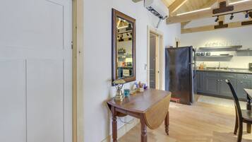 Un coin repas avec une table en bois, un miroir et une cuisine en arrière-plan.