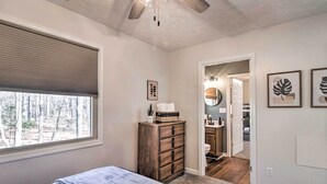 Un dormitorio con cama, cómoda, ventana con persianas, ventilador de techo y vista al exterior.