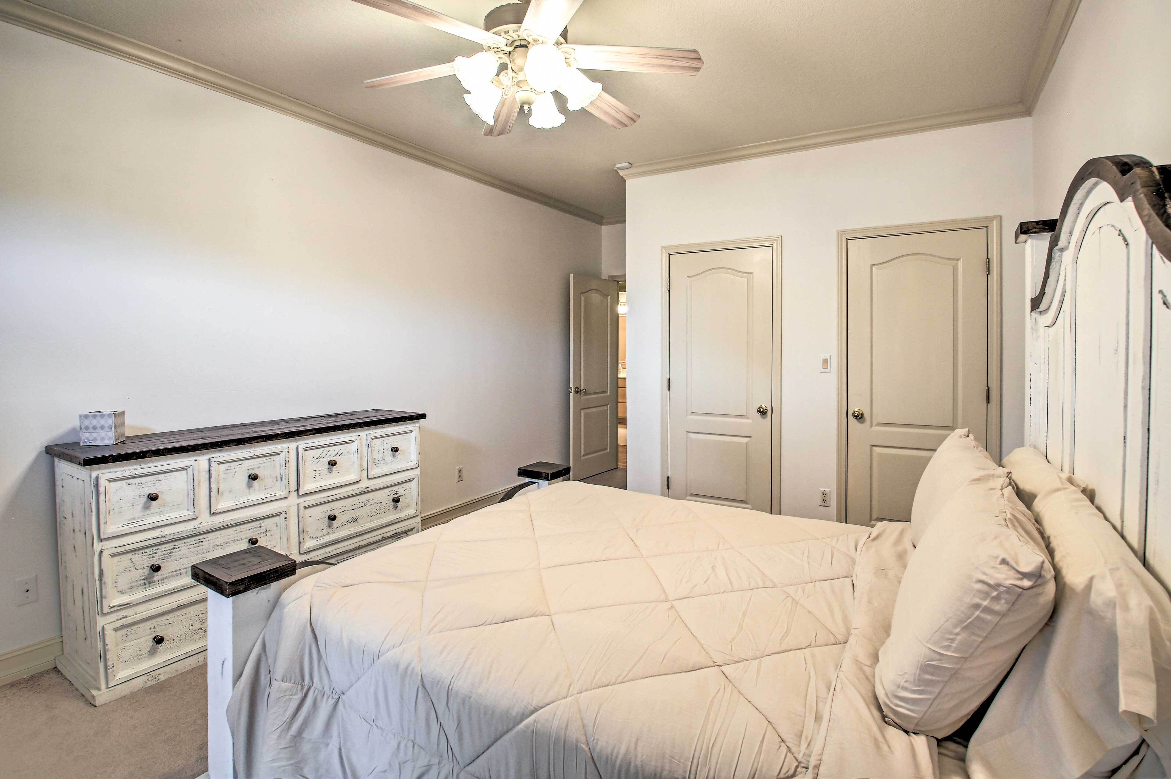 A bedroom with a bed, dresser, and two doors.