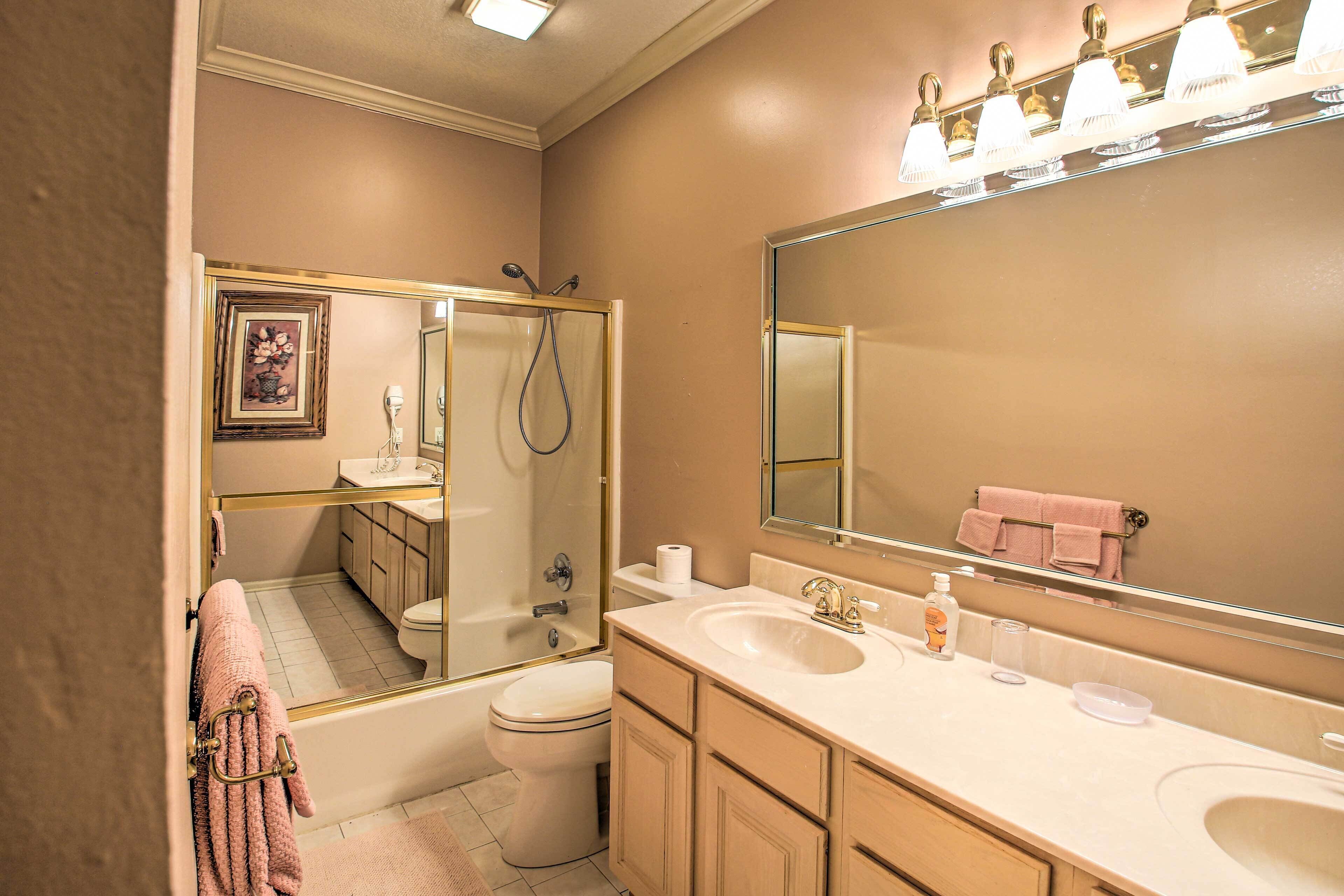 Une salle de bain avec une baignoire, des toilettes, un lavabo et un grand miroir.