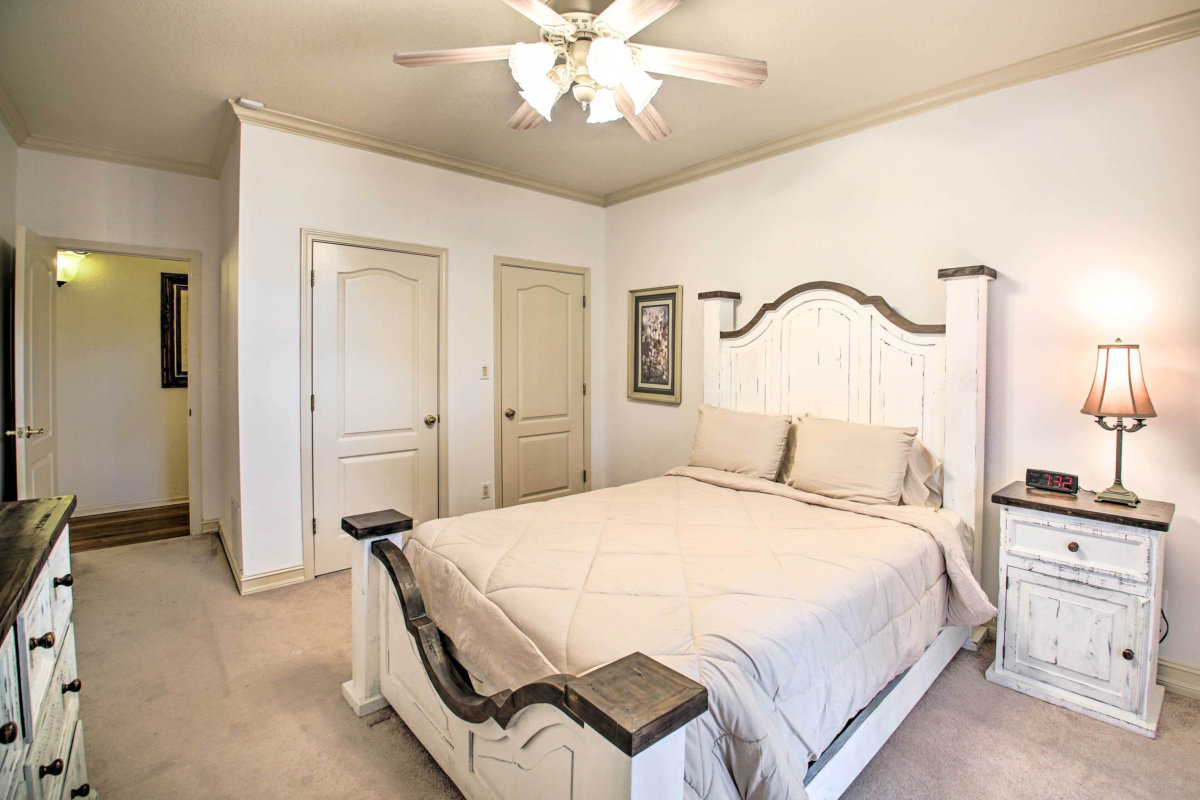 A bedroom with a bed, a nightstand, a dresser, and a ceiling fan.