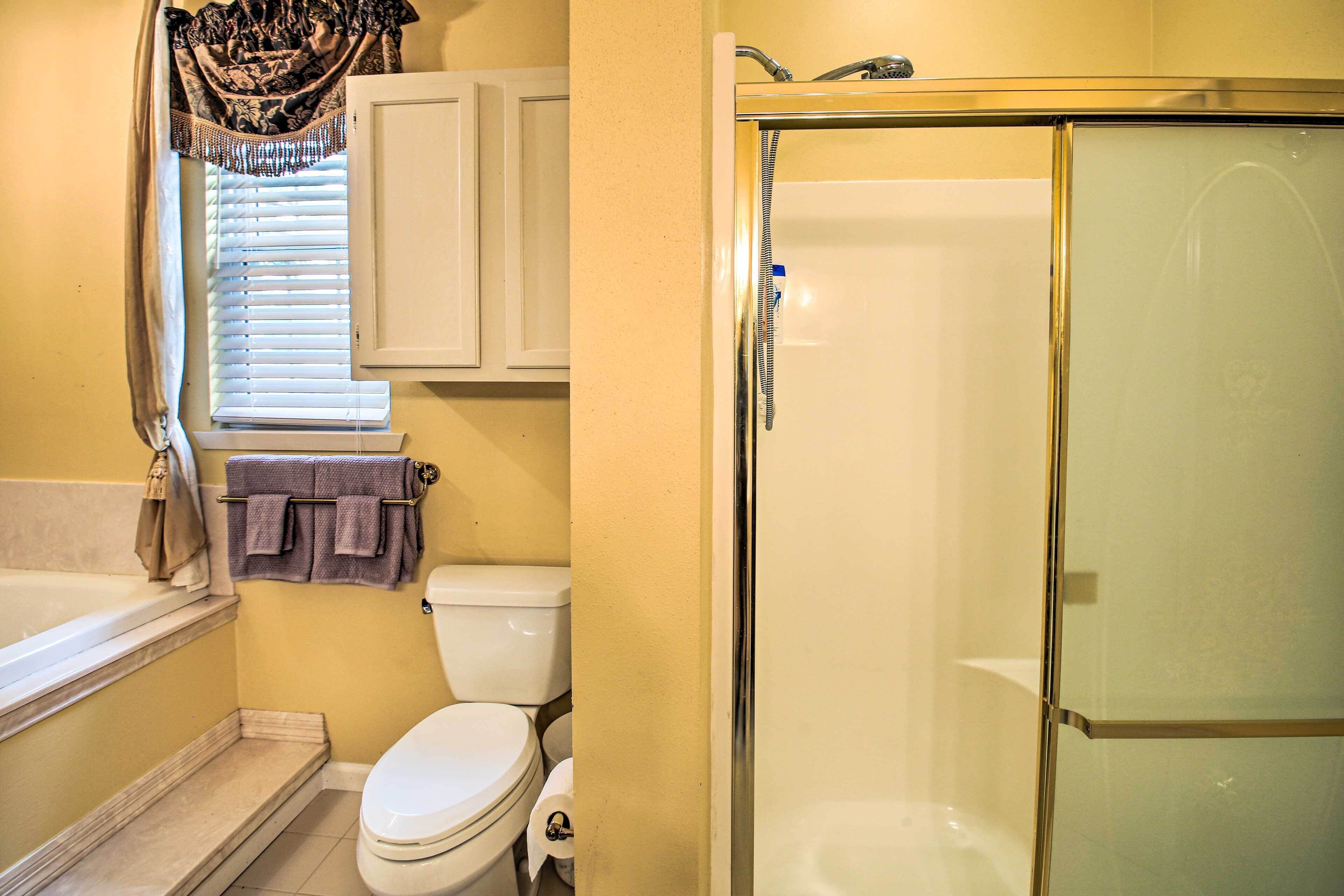 A bathroom with a bathtub, toilet, and glass-enclosed shower.