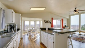 A spacious kitchen with white cabinets, a large island, and a view of the city. - Moab House Near Arches Nat'l Park & Canyonlands! (Moab)