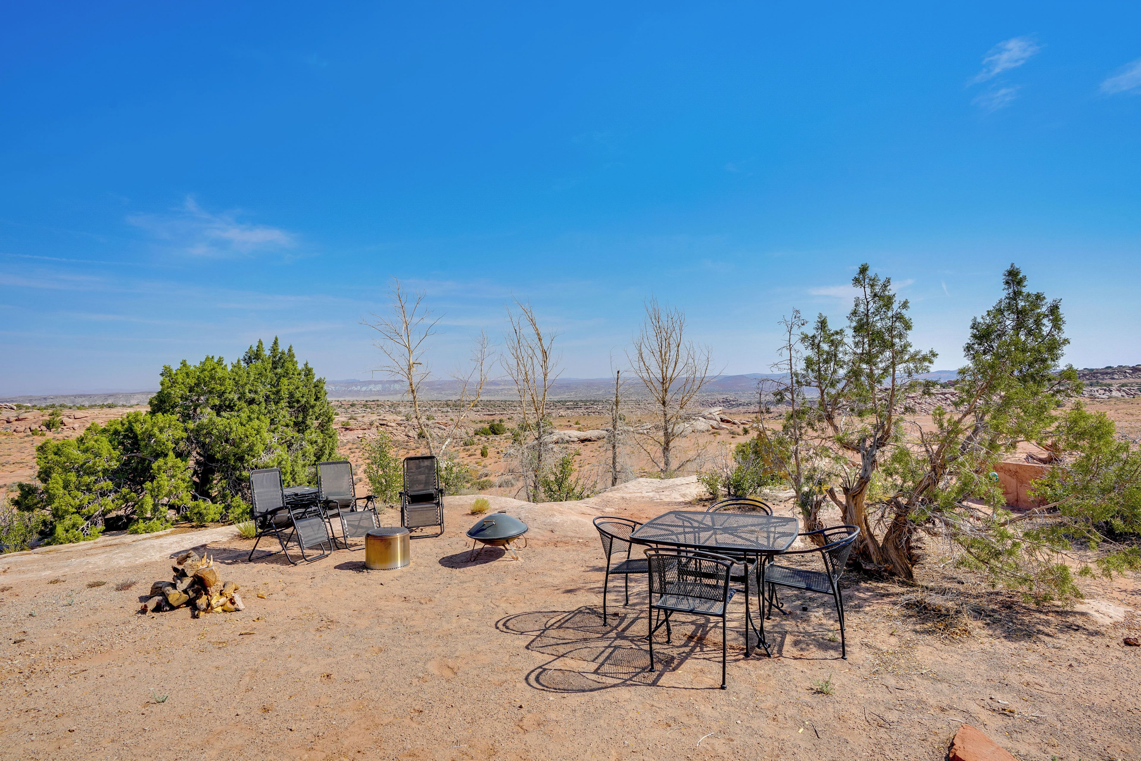 An outdoor dining area with a table and chairs, a grill, and a fire pit.
