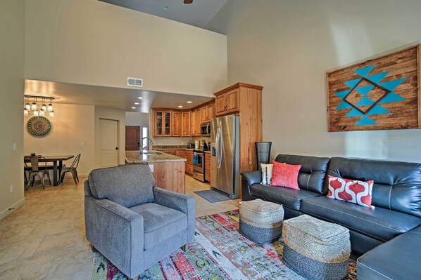 A spacious living room with a gray sofa, a black leather couch, and a colorful rug.