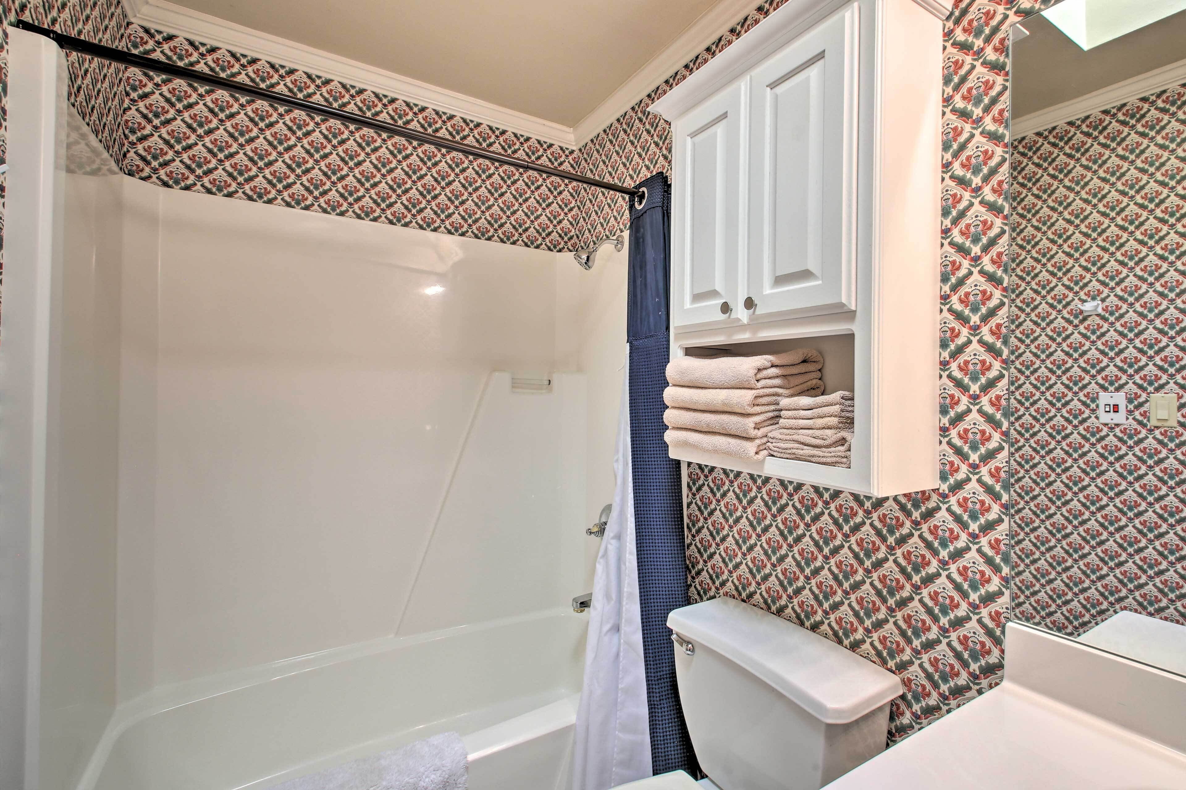 Een badkamer met een bad, toilet en een handdoekrek met opgevouwen handdoeken.