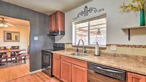 A modern kitchen with granite countertops, wooden cabinets, a dishwasher, and a window with a view.