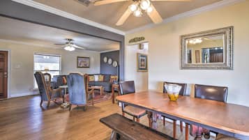 A dining area with a wooden table, chairs, and a bench. There is a ceiling fan above the table.