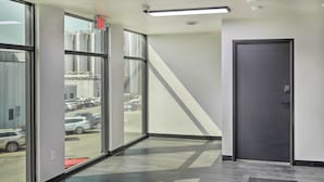 A modern hallway with large windows, a dark door, and a patterned floor. - Lake Norden Apartment w/ Spacious Balcony! (Lake Norden)