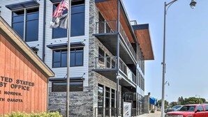 A multi-story building with a modern architectural design, featuring large windows and a prominent American flag. - Lake Norden Apartment w/ Spacious Balcony! (Lake Norden)