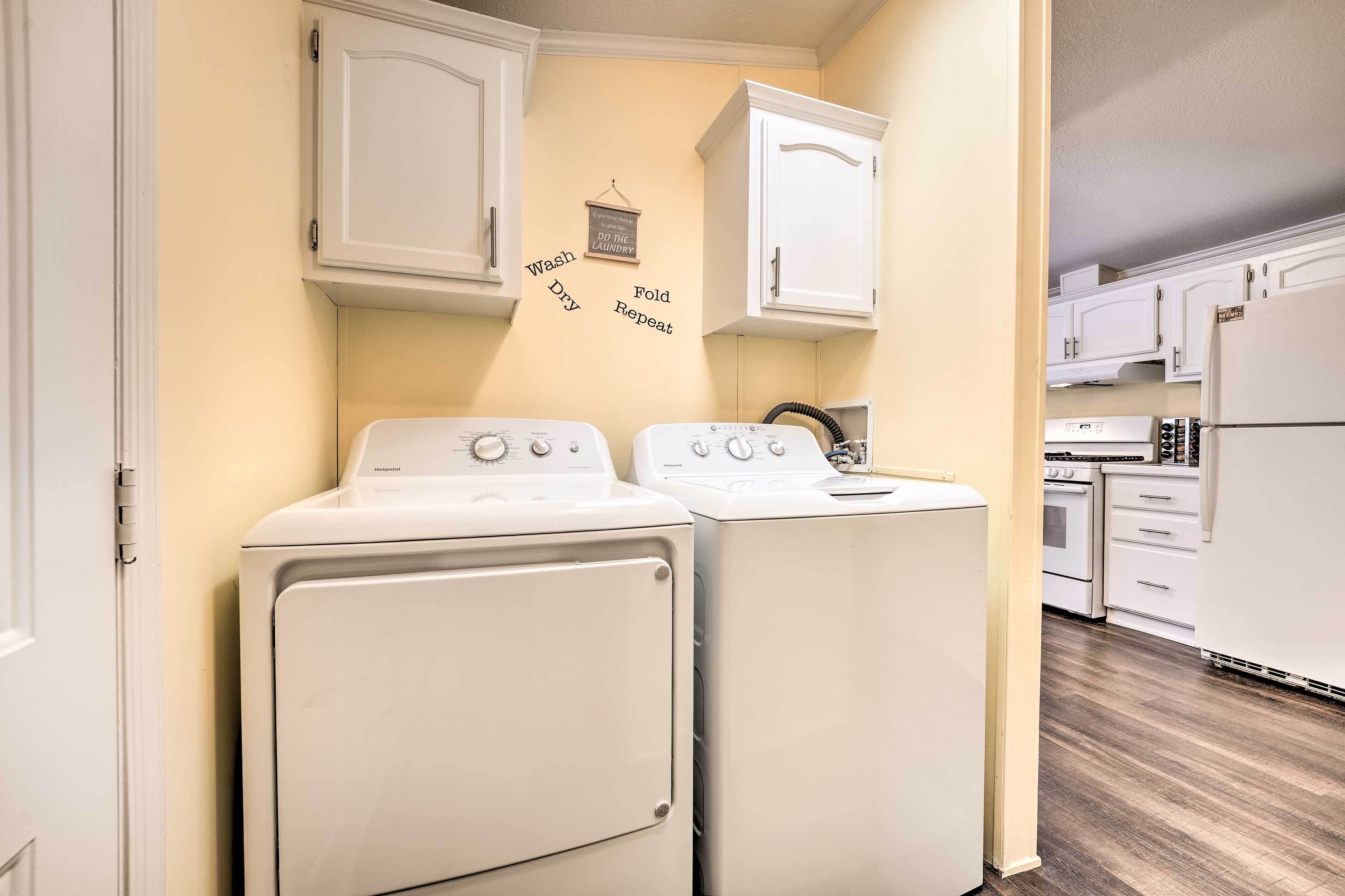A laundry room with two white washing machines and a cabinet above them.