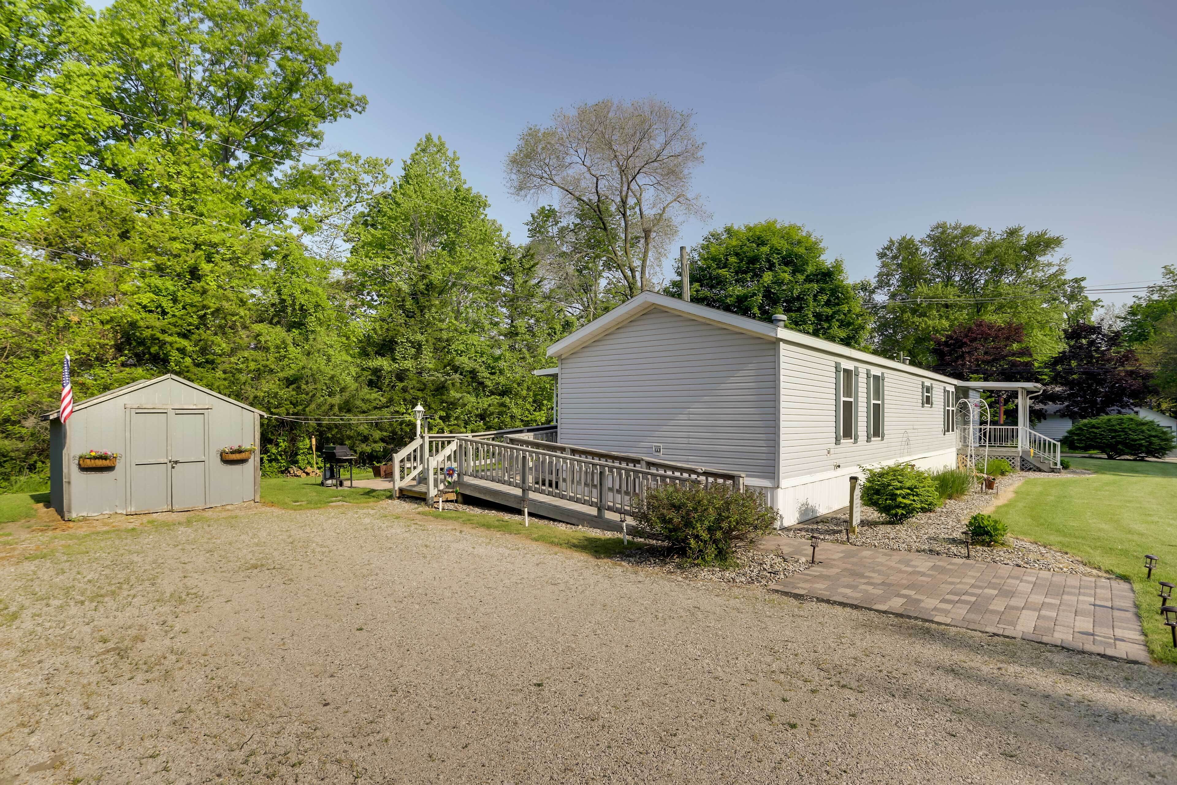 A single-story house with a front porch, a small attached garage, and a gravel driveway.