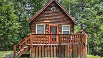 A log cabin with a wooden deck and stairs leading to the entrance.