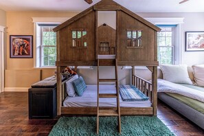 Uma cama beliche com design de casinha de madeira, uma escada e um tapete verde.