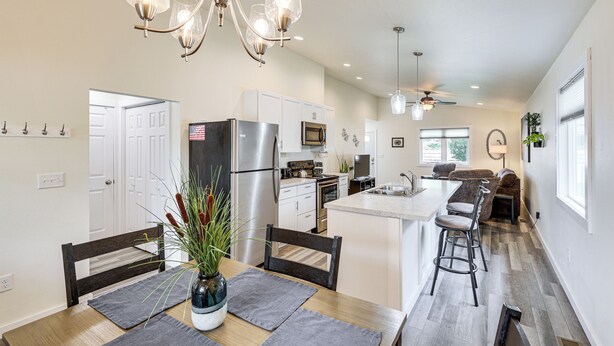 Una cocina moderna con una isla central, electrodomésticos de acero inoxidable y un comedor con mesa y sillas de madera.