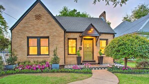 A brick house with a green door, a small porch, and a well-maintained garden with pink flowers. - Newly Updated & Charming Azalea District Home (Tyler)
