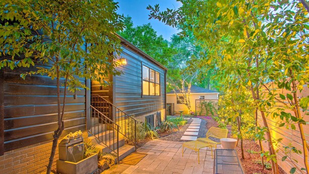 A house with a wooden exterior, a stone pathway, and outdoor seating. - Newly Updated & Charming Azalea District Home (Tyler)