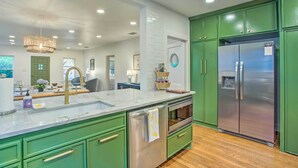 A modern kitchen with green cabinets, stainless steel appliances, and a marble countertop. - Newly Updated & Charming Azalea District Home (Tyler)