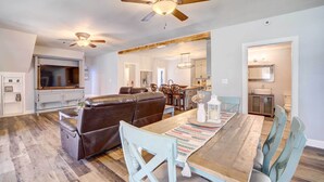A spacious living area with a wooden dining table, light blue chairs, a brown leather sofa, and a ceiling fan. - Game Room + Large Backyard: Afton Home! (Afton)