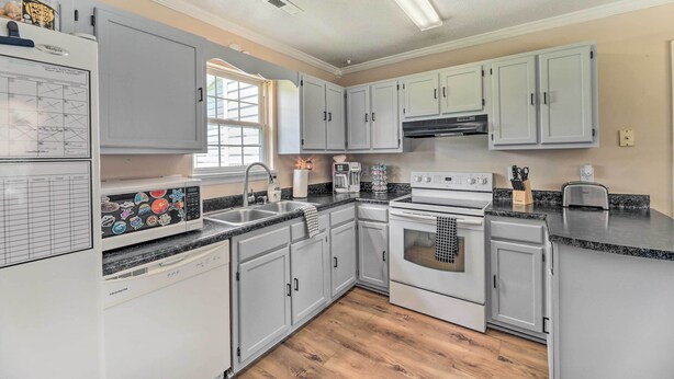 A modern kitchen with grey cabinets, a built-in dishwasher, a stove, and a microwave. - Pet-friendly Jacksonville Home w/ Fenced Yard (Jacksonville)