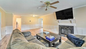 A living room with a sofa, a coffee table, a fireplace, and a television. - Pet-friendly Jacksonville Home w/ Fenced Yard (Jacksonville)