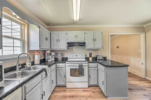 A kitchen with a central island, white cabinets, a stainless steel sink, and a built-in oven.