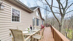 A wooden deck with a table and chairs, a railing, and a house in the background. - Resort Home on Mountain Golf Course w/ Deck & View (McGaheysville)
