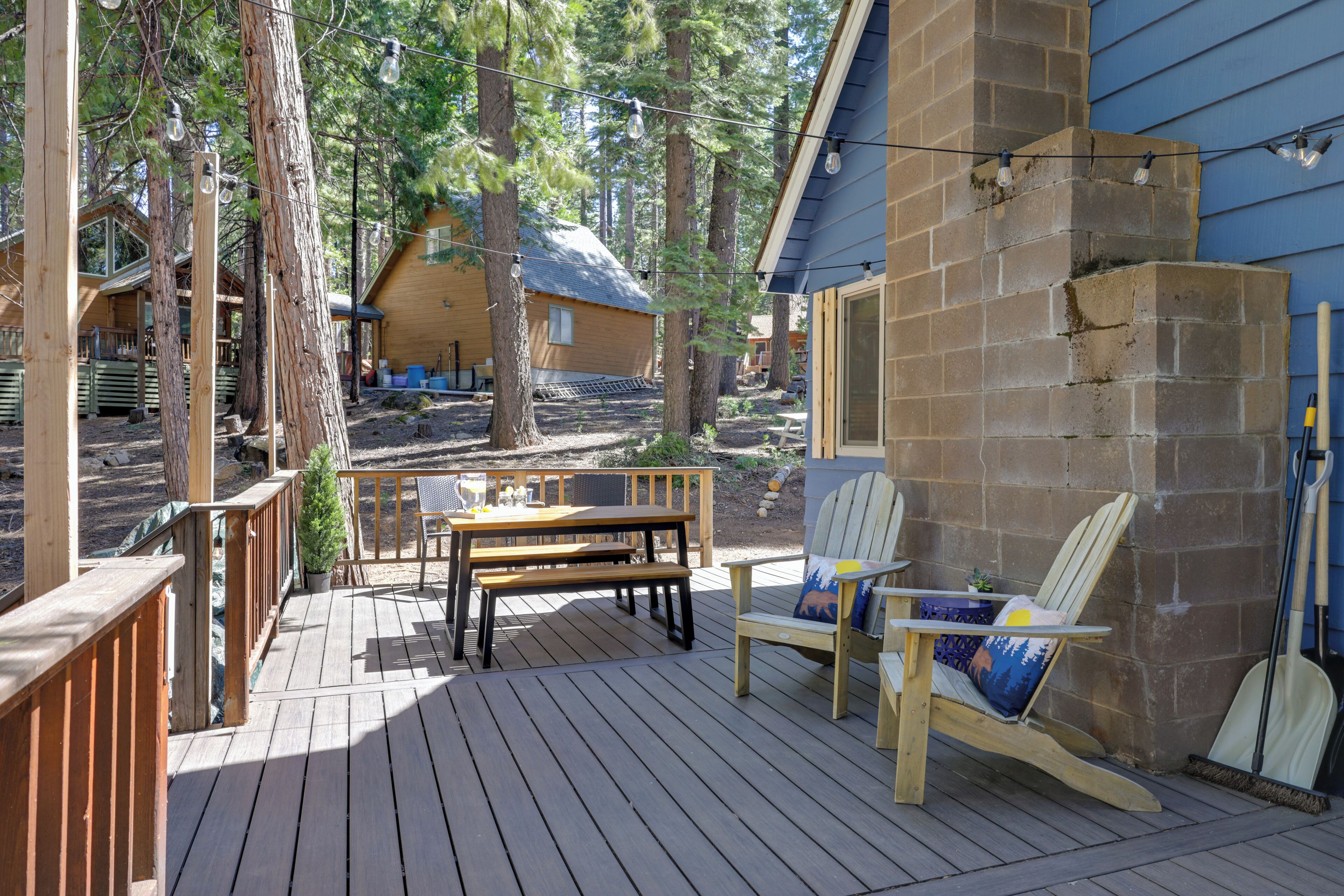 A wooden deck with a table and chairs, surrounded by trees.