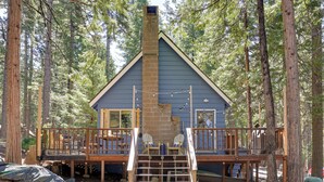 A cabin with a wooden deck, a chimney, and a staircase leading to a balcony with chairs. - 3 Mi to Big Trees State Park: Cabin w/ Scenic Deck (Arnold)