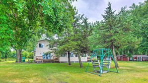 A residential property with a house, a swing set, and a well-maintained lawn. - Lakefront Spicer Cabin w/ Dock & 2 Kayaks! (Spicer)