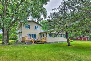 A two-story house with a deck, surrounded by trees and a well-maintained lawn. - Lakefront Spicer Cabin w/ Dock & 2 Kayaks! (Spicer)