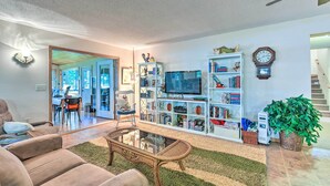 A living room with a sofa, coffee table, bookshelf, television, and a staircase. - Lakefront Spicer Cabin w/ Dock & 2 Kayaks! (Spicer)