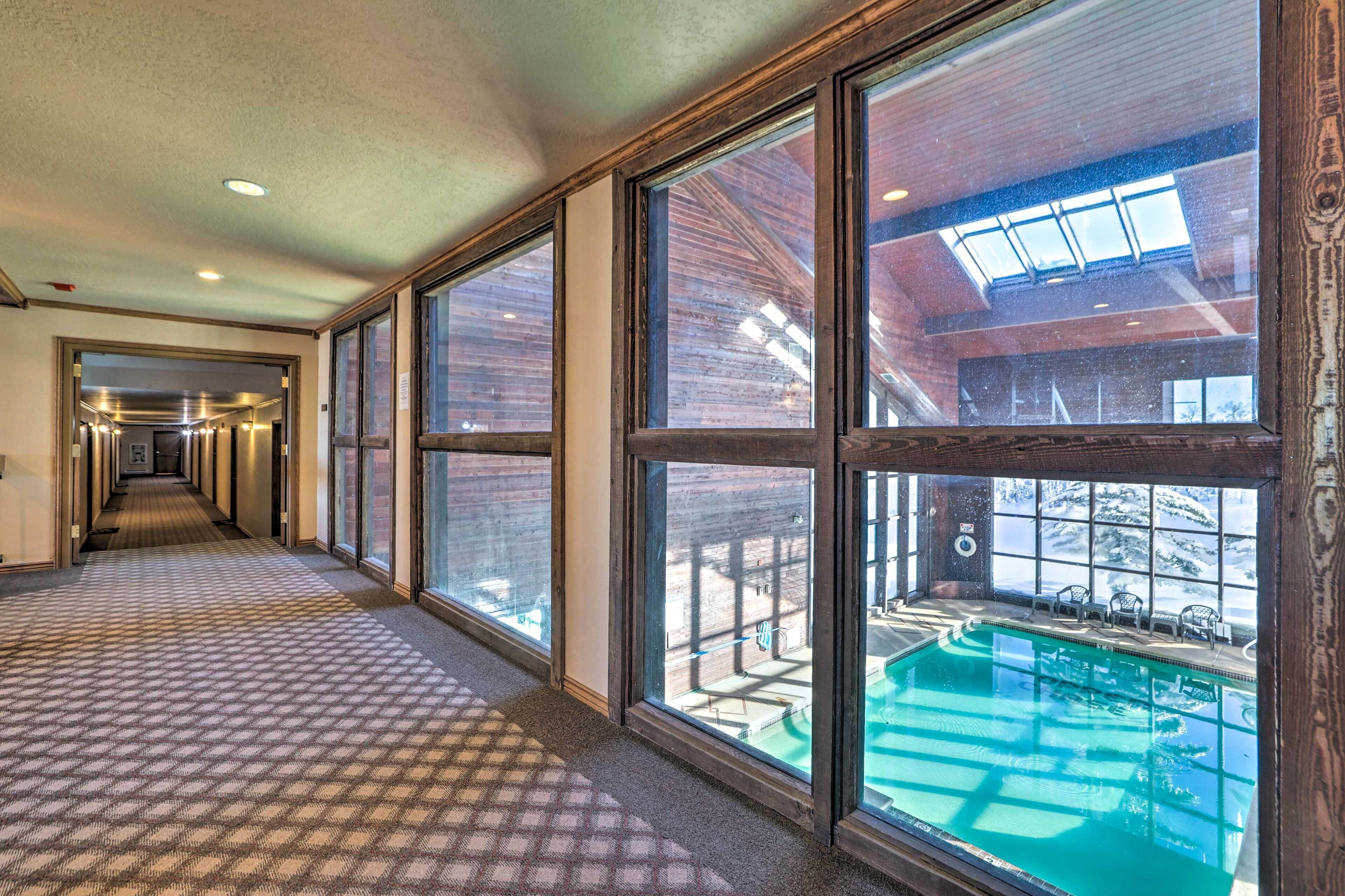 A hotel corridor with large windows, a pool area, and a view of the outdoors.