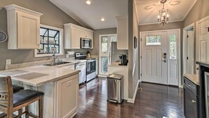 A modern kitchen with white cabinetry, a central island, stainless steel appliances, and a chandelier. - Pinehurst Gem on Golf Course & Putting Green! (Pinehurst)