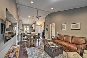 A spacious living room with a leather sofa, a coffee table, and a dining area with wooden chairs. - Pinehurst Gem on Golf Course & Putting Green! (Pinehurst)
