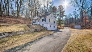 A two-story house with a stone retaining wall, a garage, and a driveway leading to the house. - Pet-friendly Mohnton House Near Golf Course! (Mohnton)