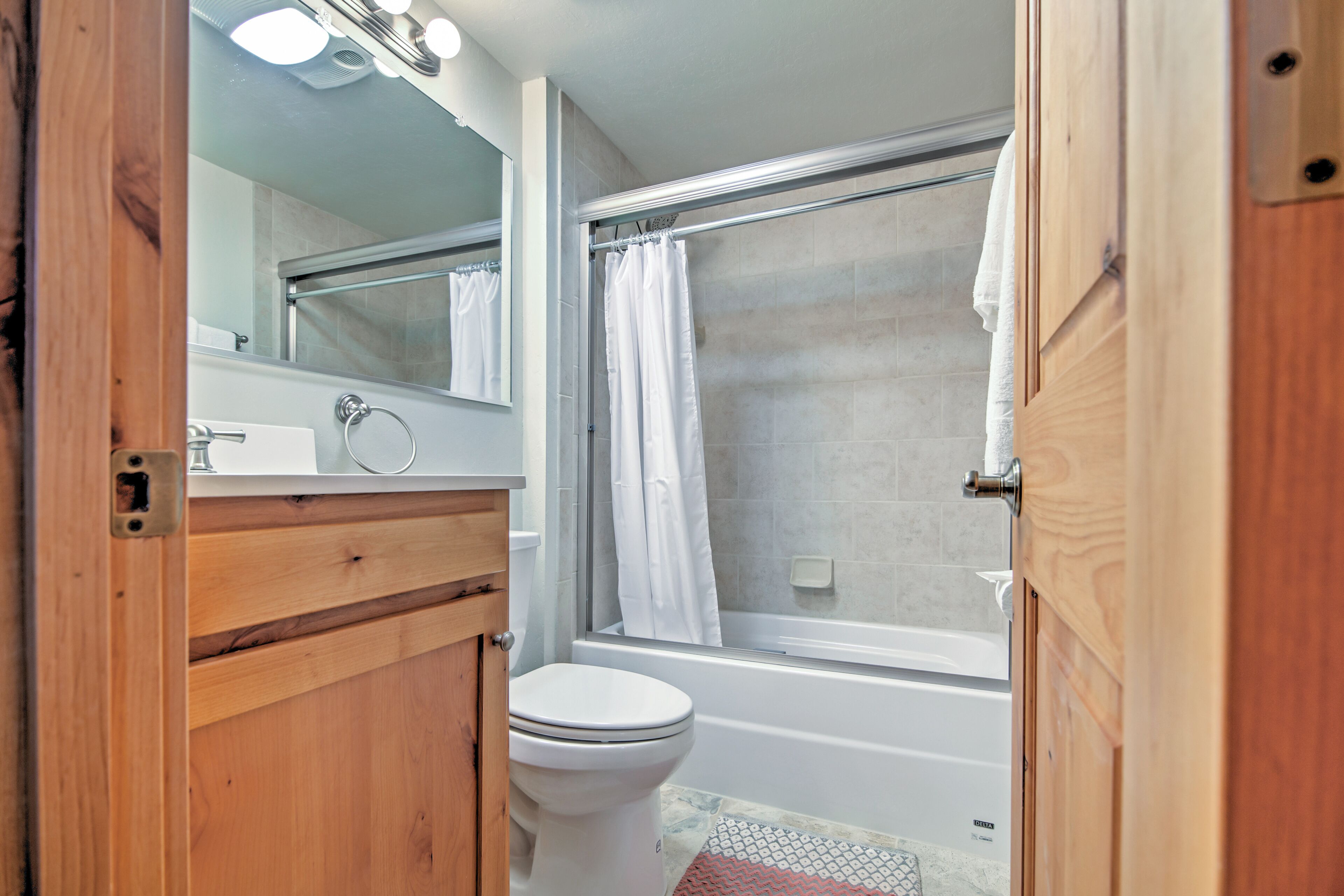 Une salle de bain comprenant des toilettes, un lavabo, un miroir, une douche avec un rideau et une baignoire.