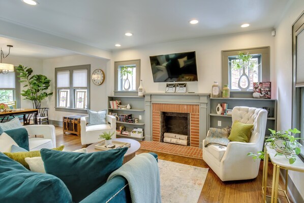 A modern living room with a fireplace, comfortable seating, and a flat-screen TV. - Renovated Lubbock Home - Walk to Texas Tech! (Lubbock)