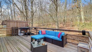 Een terras met een blauwe modulaire bank, een tafeltje met een waterkoker, en een barbecue.