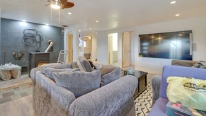 Een moderne woonkamer met een grijze zithoek, een plafondventilator, een flatscreen-tv en een kamerbreed tapijt met een patroon.