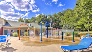 A water park with a water play area, blue lounge chairs, and a building in the background. - Pocono Mountain Home w/ 3 Community Lakes! (Gouldsboro)